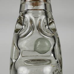 Neck of clear glass bottle containing marble stopper.
