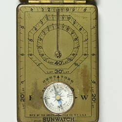 Open metal case containing compass and sundial. Detail.