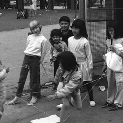 Group of children watching and playing elastics.