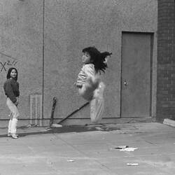Three girls playing elastics, one jumping.
