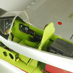 Silver model aeroplane. Detail of green cockpit area.
