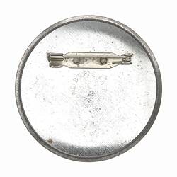Round badge with metal back and horizontal pin.