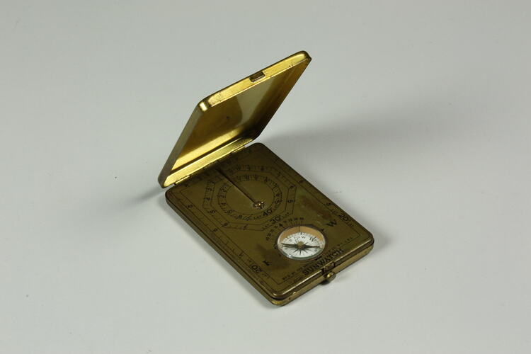 Open metal case containing compass and sundial.