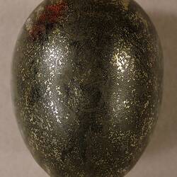 Metal hen egg with worn gold surface.