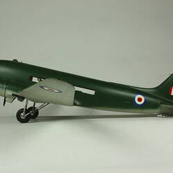 Dark green two propeller aeroplane model with two wheels and painted red, white, blue flag and roundles.
