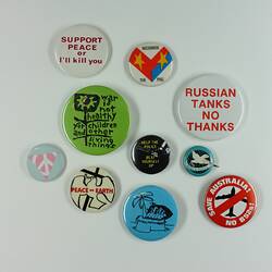 Mix of ten round coloured badges varying in size with words or images relating to peace.