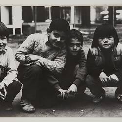 Four young boys playing a marbles game.