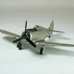 Model aeroplane, silver with a black propeller and wheels.