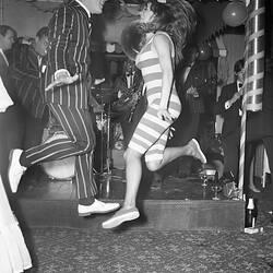 Man and woman dancing in striped costumes.