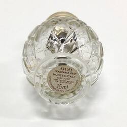 Underside of round glass perfume bottle showing label.