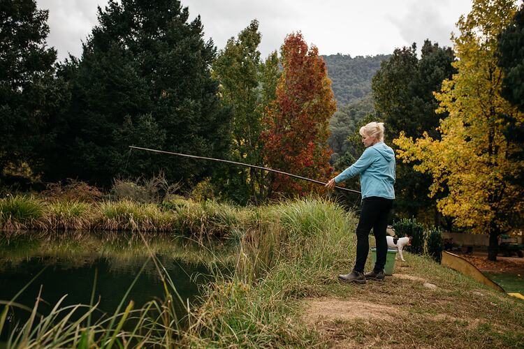 Woman fishing in a pond with bamboo rod.