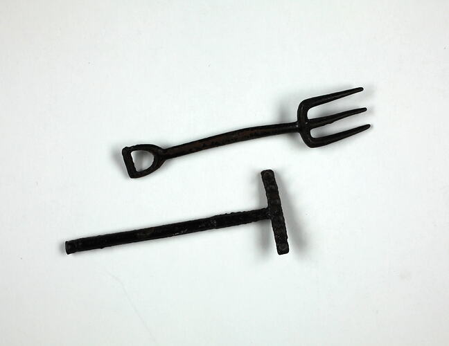 Toy pitchfork and rake, lying down.