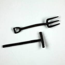 Toy pitchfork and rake, lying down.