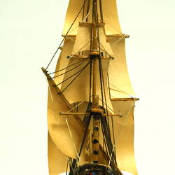 Rear view of three masted ship with wooden hull.