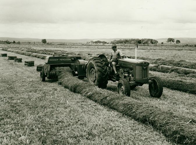 Man driving an tractor with a Pick-Up Baler through a field with a perfect windrow of hay.
