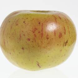 Wax model of an apple painted green with red flecks.