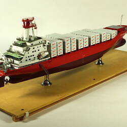 Container ship with red hull three quarter view.