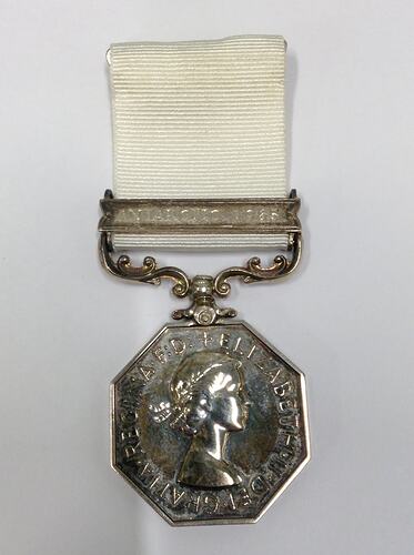 Octagonal silver medal with white ribbon.
