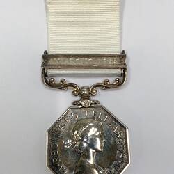 Octagonal silver medal with white ribbon.