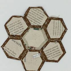 Hexagonal printed card backing for coloured fabric patches that are stitched together.