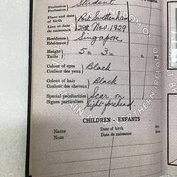 Open passport. Left white page has black printing and handwritten text.