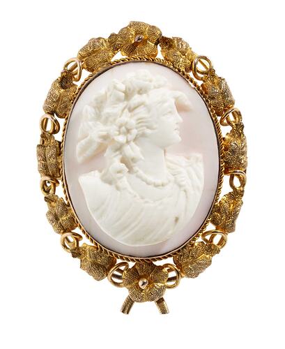 Oval brooch with gold framing white cameo relief woman facing right. Frame is gold leaves and tendrils.