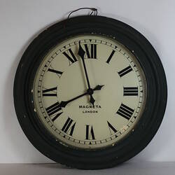 Circular wooden clock painted dark green with white face.
