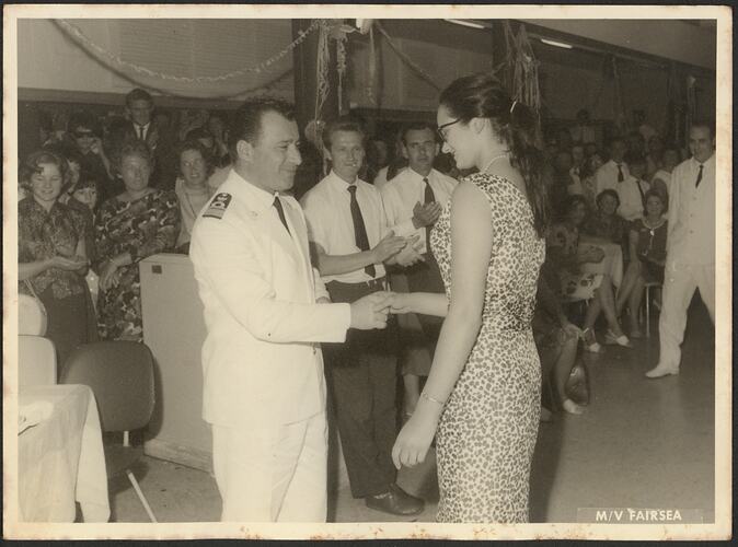Woman being presented to the ship's captain who wears a white uniform.