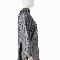 Short shift-style dress made from irregular pieces of pewter grey leather to resemble reptilian scales. Right profile.