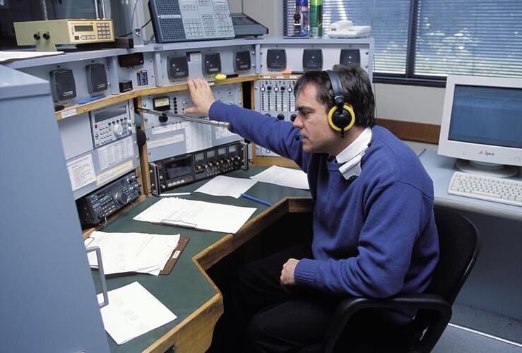 Michael Greenwood with headphones, at console. Melbourne Coastal Radio Station, Cape Schanck, Victoria