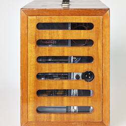 Back view of rectangular wooden box with horizontal slats and handle on top.