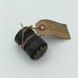 Section of metal cylinder containing metal cables. Paper tag attached.