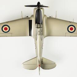Top view of model aeroplane, silver with a black propeller and wheels.