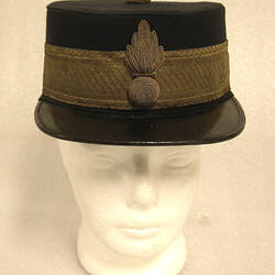 Black cap with gold braid band around base of crown, with gold badge in centre.