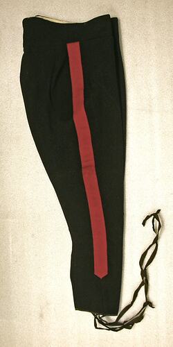 black pants with single red stripe running up side of pantleg, long fabric strips attached to ankles.