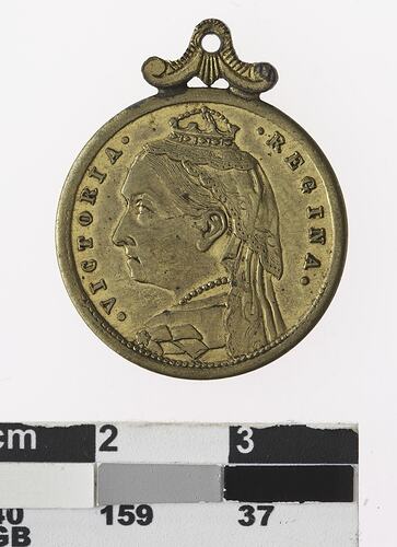 Round silver coloured medal with profile of crowned woman, text surrounding and multicoloured ribbon.