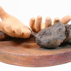 Side view of sculpture of two clay hands.