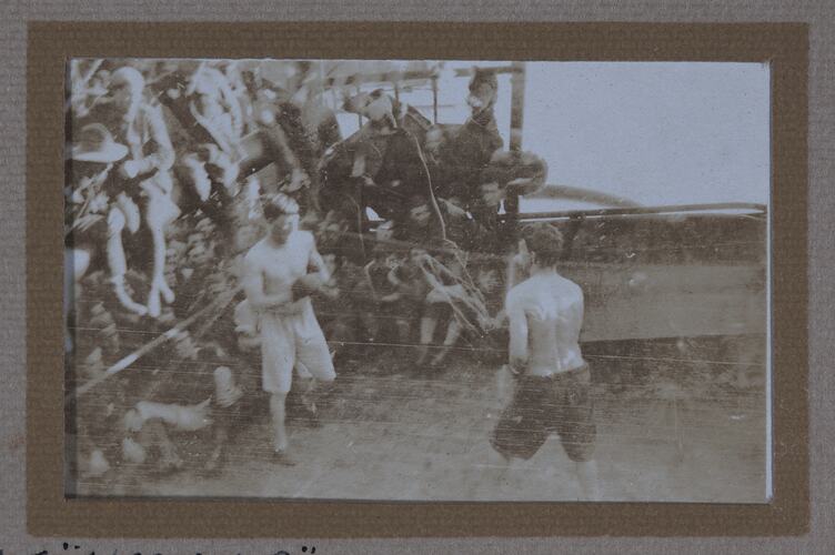 Two men boxing with audience on left side.