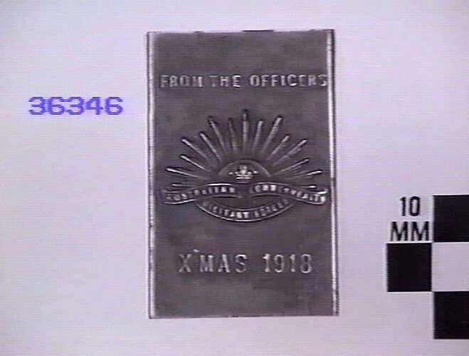 Steel matchbox holder embossed on one side with rising sun badge and text.