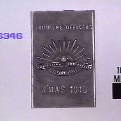 Steel matchbox holder embossed on one side with rising sun badge and text.