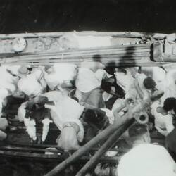 View from above of a lifeboat with passengers alongside a larger ship.