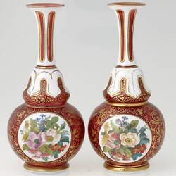 Pair of ruby red and white blown glass vases with gilt arabesque style tendril design, and enamelled floral panels.