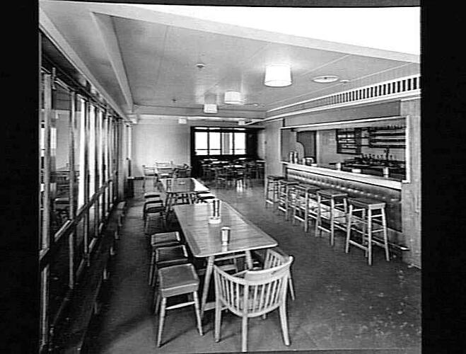 Ship interior. Long table with chairs at left, bar with stools at right.
