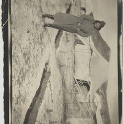 Woman in cold weather clothing standing on snowy ground next to tents.