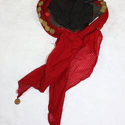 Red scarf-like headdress with metal discs along edges.