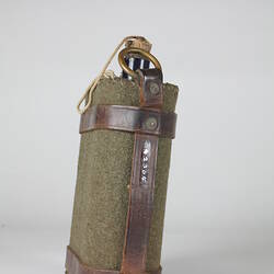 Green fabric water bottle holder with brown leather straps, side view.