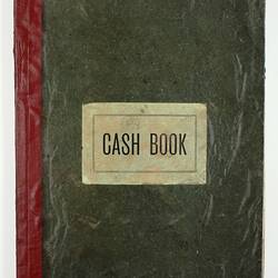 Closed book with green cover and red spine, cover reads 'Cash Book',