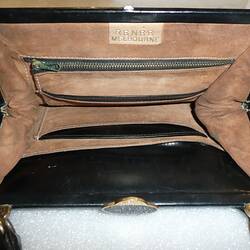 Tan interior of black, fur-covered handbag with pouches.