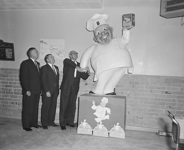 Brockhoff Biscuit Co, Men Standing with a Promotional Figure, Burwood, Victoria, 26 Jun 1959