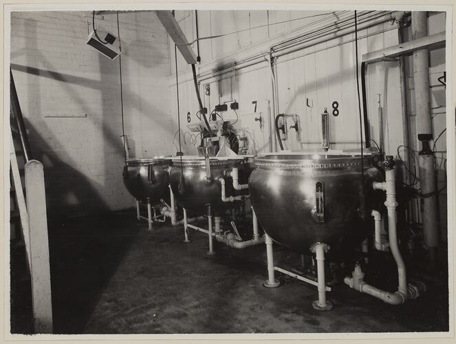 Industrial interior, dominated by three large round vats.